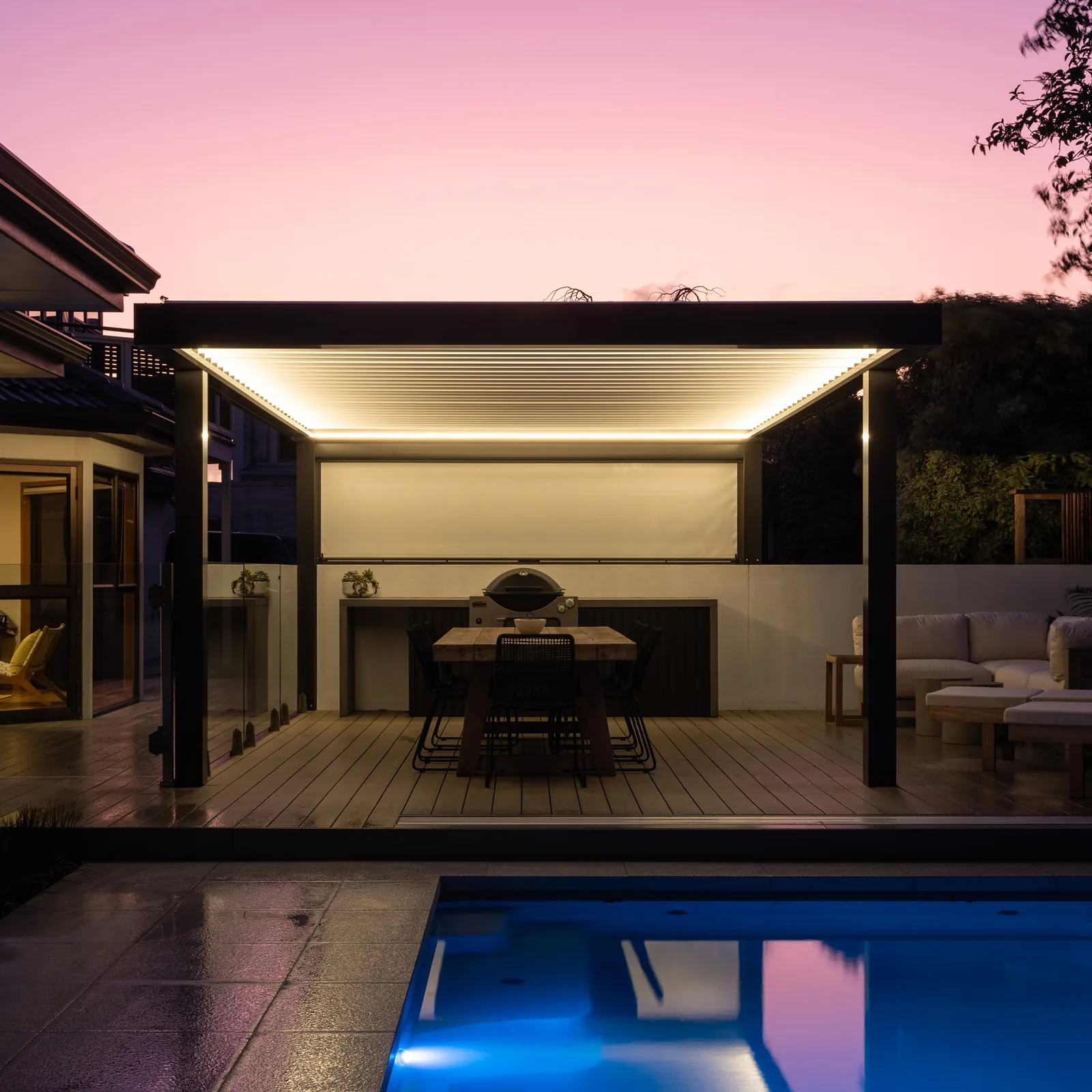 Integrated warm white LED strip lighting on an EXO louvre roof at dusk beside a pool