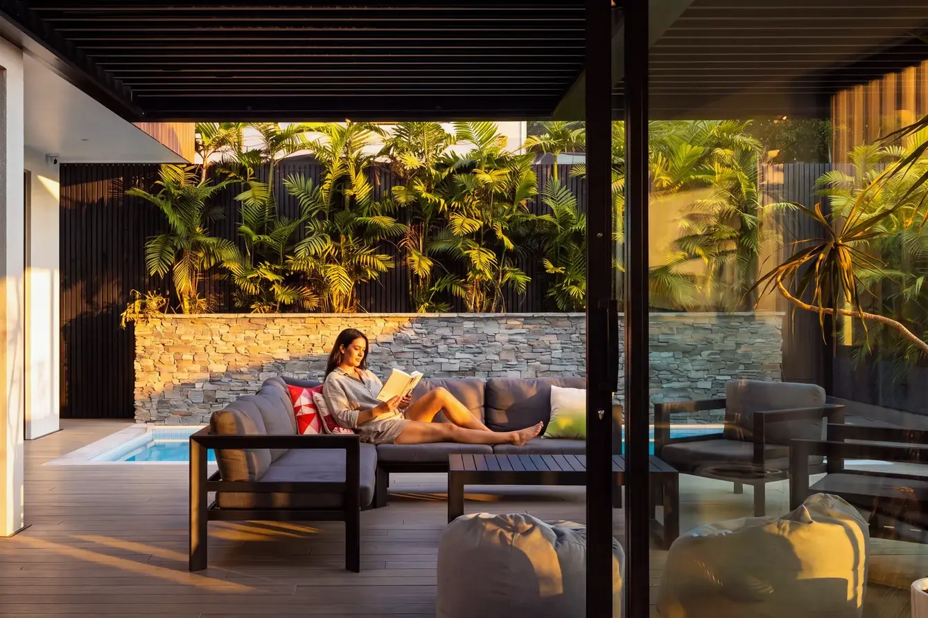 Woman relaxing with a book in the shade of an adjustable EXO louvre roof